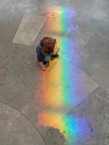 my so crouching over a rainbow that formed on the ground