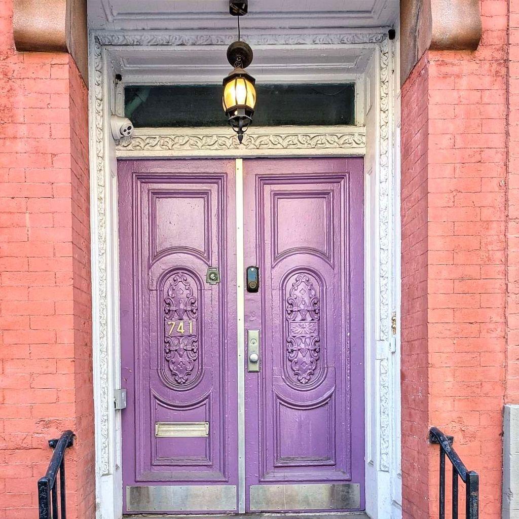 A set of regal purple double doors at number 741, featuring elaborate oval carvings and a warm glowing lantern above.