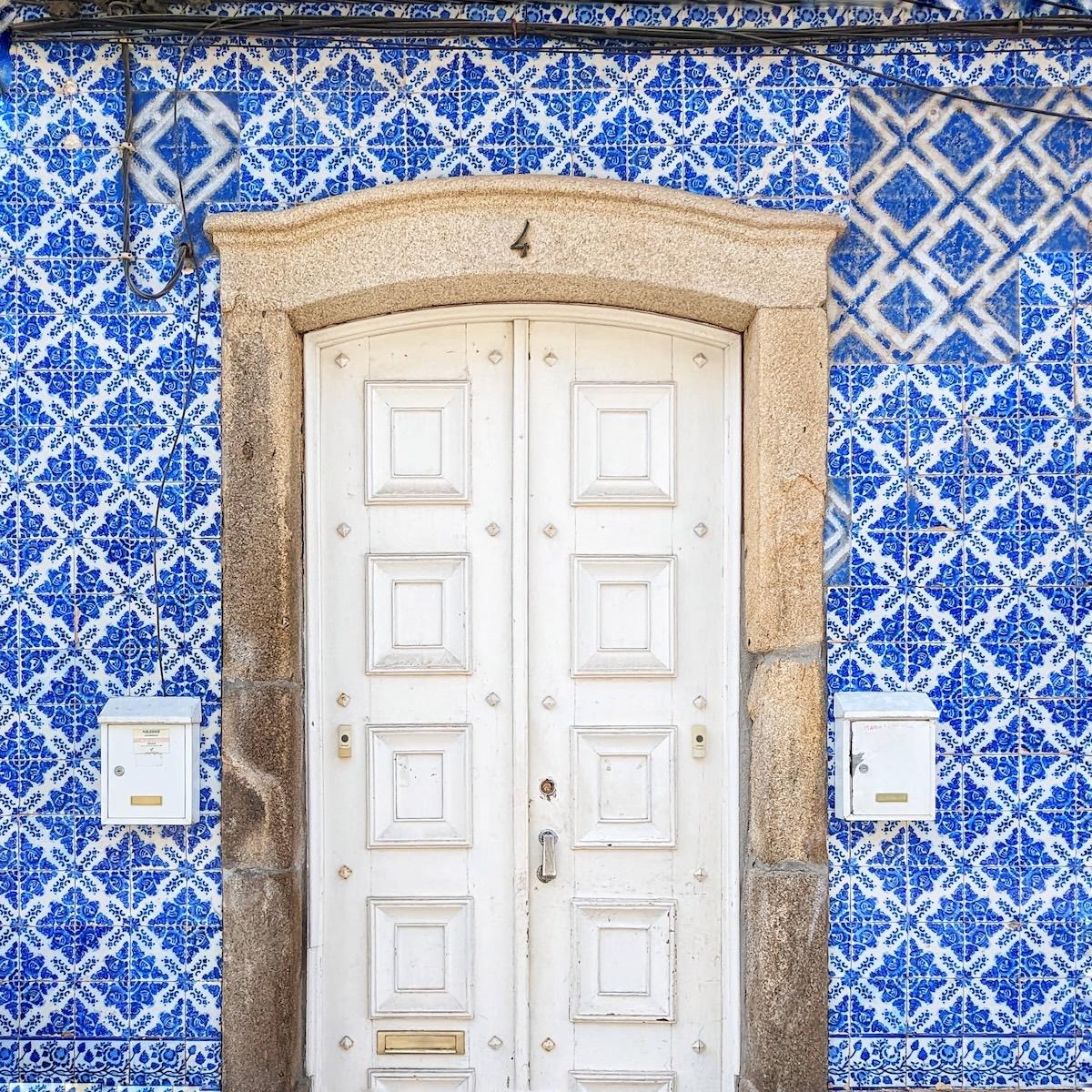 A clean white multi-paneled door numbered 4, surrounded by a wall of intricate blue and white Portuguese tiles (azulejos).